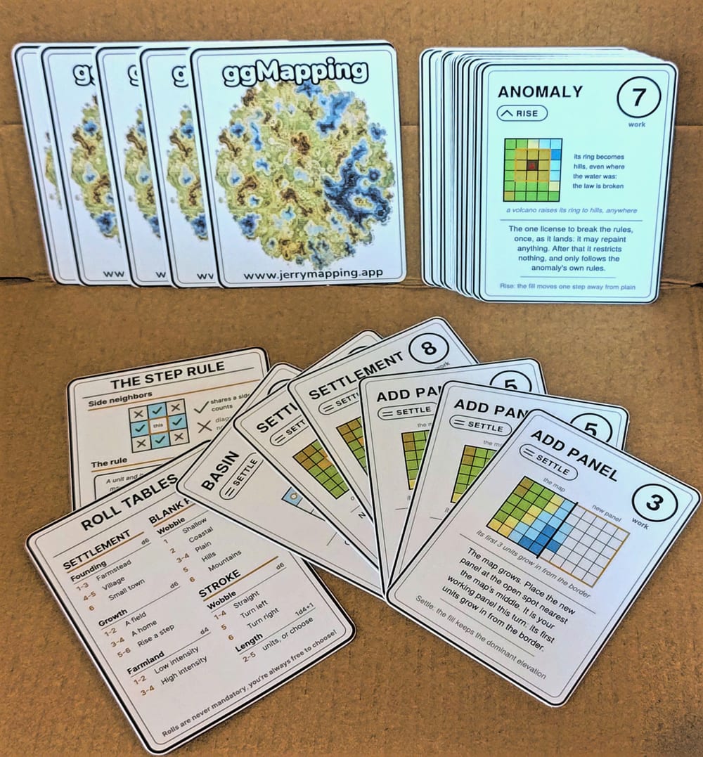 The printed ggMapping deck laid out: map-backed cards, the Anomaly card, the Step Rule cheat card and the roll tables